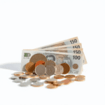 Diverse monede și bancnote internaționale aranjate artistic pe o suprafață netedă, având în fundal simboluri abstracte legate de finanțe.