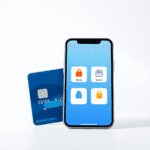 Prim-plan cu un card bancar și un smartphone care afișează o interfață simplificată a unei aplicații bancare, cu pictograme pentru transfer de bani...