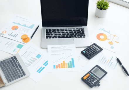 Spațiu de lucru luminos și ordonat, cu laptop, calculator, documente financiare bine organizate și pictograme abstracte discrete reprezentând fluxu...